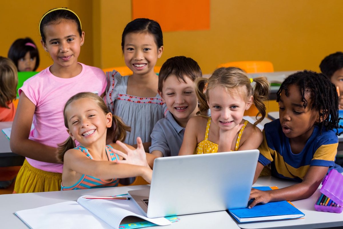 Students crowded around a laptop together in class, laughing
