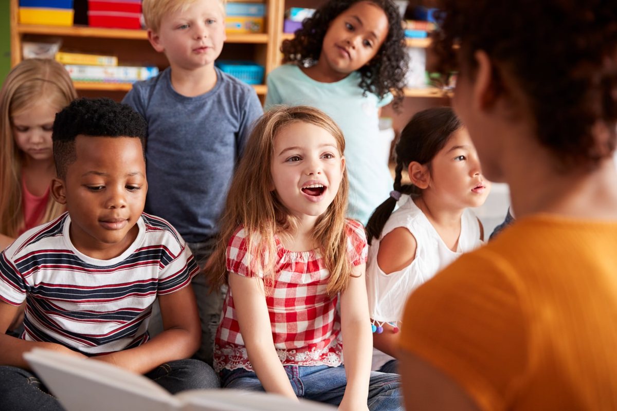 Students listening closely as a book is read aloud in the classroom library